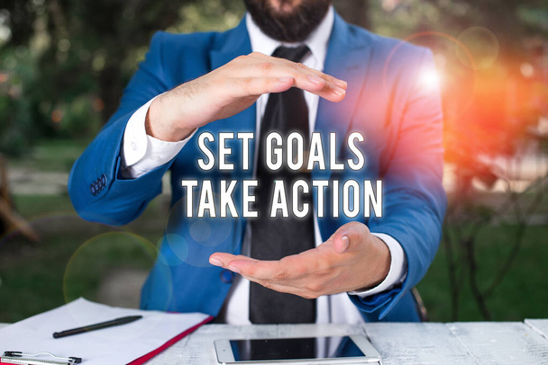 Εννοιολογική γραφή χεριών που δείχνει Set Goals Take Action. Επιχειρηματική φωτογραφία προβάλλοντας Πράξη σε ένα συγκεκριμένο και σαφή σχέδια Ο άνθρωπος μπροστά από το τραπέζι. Κινητό τηλέφωνο και σημειώσεις στο τραπέζι. - Φωτογραφία, εικόνα