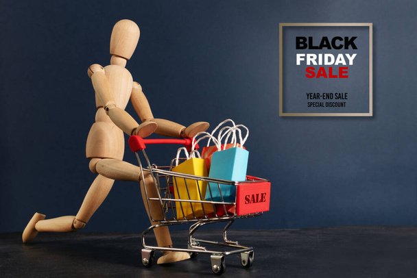 Black Friday sale, wooden doll running with shopping cart - Valokuva, kuva