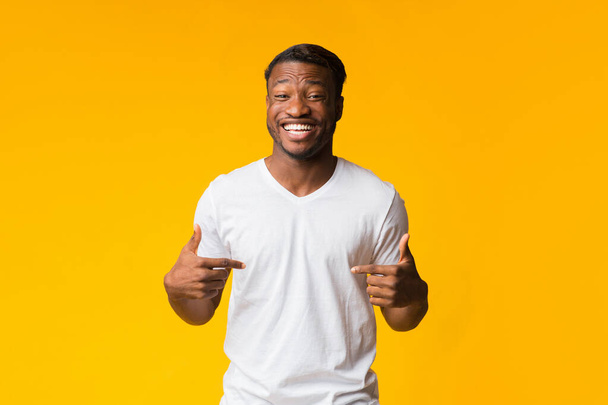 Fekete ember ujjal mutogat magára mosolyog át sárga háttér - Fotó, kép