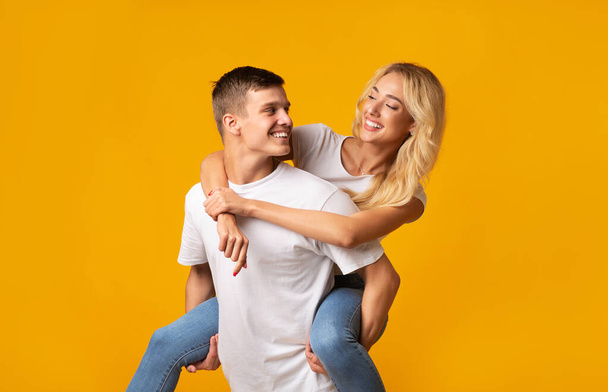 Romantic young man giving piggyback ride to his happy girlfriend - Photo, Image