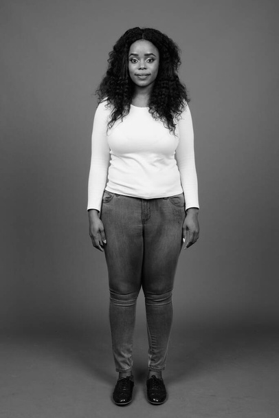 Siyah ve beyaz gri arka planda Afro saçlı güzel Afrikalı bir kadının stüdyo fotoğrafı. - Fotoğraf, Görsel