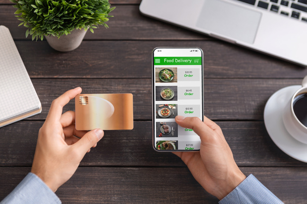 Mann benutzt Kreditkarte und Smartphone mit Essenslieferanwendung - Foto, Bild
