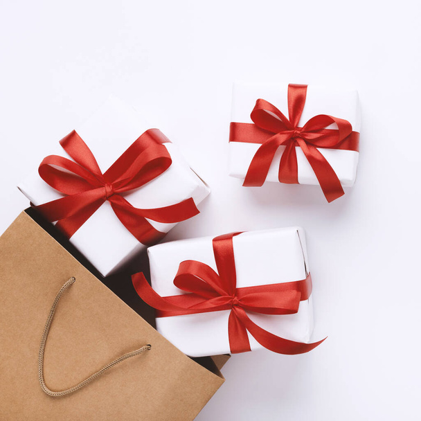 Πολλά χριστουγεννιάτικα δώρα με κόκκινες κορδέλες και τσάντα για ψώνια - Φωτογραφία, εικόνα