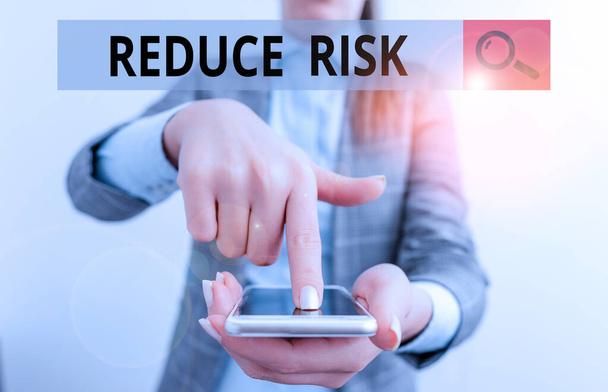 Writing note showing Reduce Risk. Business photo showcasing lessen the potential damage that could be caused by a hazard Business woman points with finger on touch screen. - Photo, Image