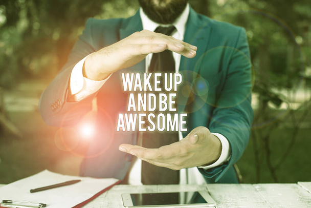 Conceptual hand writing showing Wake Up And Be Awesome. Business photo showcasing Rise up and Shine Start the day Right and Bright Man in front of table. Mobile phone and notes on the table. - Photo, Image