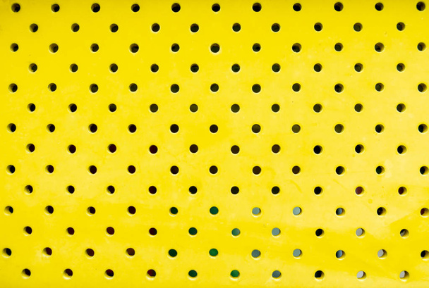 Tausta: Keltainen metallilevy, jossa on yhdeksän mustaa aukkoa
 - Valokuva, kuva