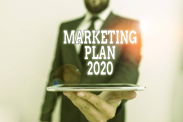 Word writing text Marketing Plan 2020. Business concept for schedule defining brand selling way in next year Male human wear formal work suit hold smart hi tech smartphone use one hand. - Photo, Image