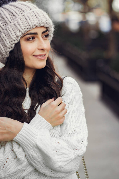 Cute brunette in a white sweater in a city - Fotó, kép