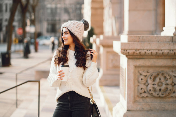 Cute brunette in a white sweater in a city - Fotoğraf, Görsel