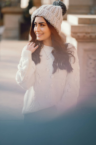 Cute brunette in a white sweater in a city - Fotoğraf, Görsel