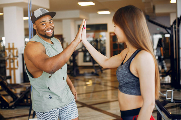 A beautiful sports couple is engaged in a gym - Foto, afbeelding