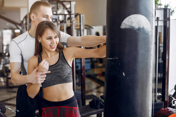 A beautiful sports couple is engaged in a gym - Foto, afbeelding