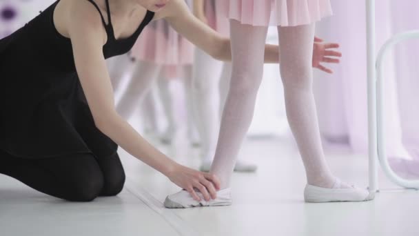 Füße unkenntlich gemachter kleiner Mädchen in weißen Socken und Ballettschuhen, deren Ballettlehrerin sie korrigiert - Filmmaterial, Video
