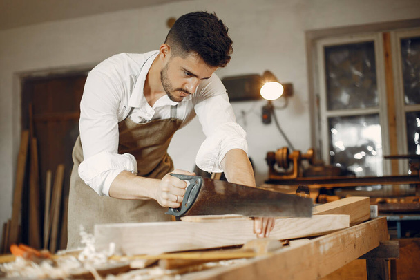 Handsome carpenter working with a wood - Zdjęcie, obraz