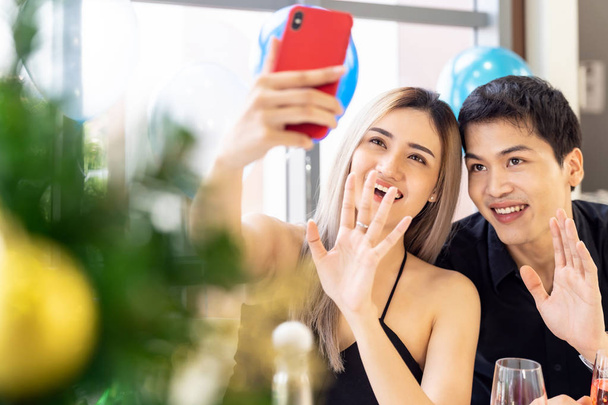 Young asian adult couple make selfie photographing for celebrateing New Year and Christmas holiday together in living room of big apartment in big city. - Zdjęcie, obraz