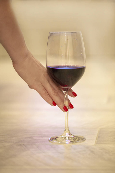mano femenina con una copa de vino tinto. concepto foto
 - Foto, imagen