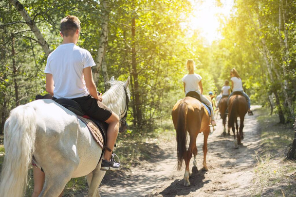 Group of teenagers on horseback riding in summer park - Photo, image