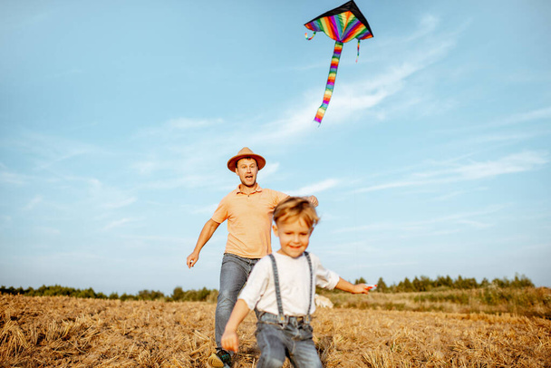 Fother e hijo volando cometa en el campo
 - Foto, imagen