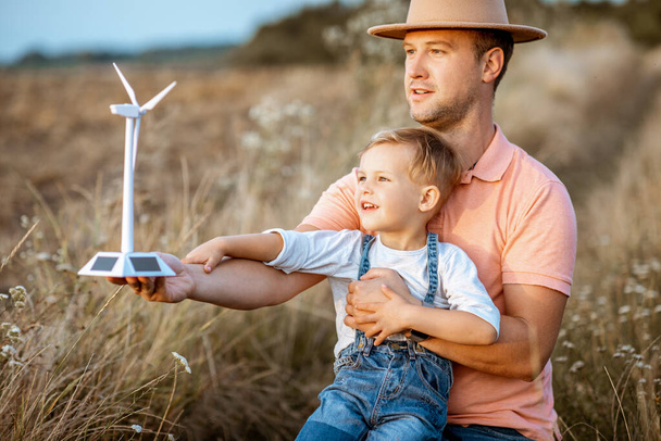 Father and young son playing with wind turbine - Foto, afbeelding