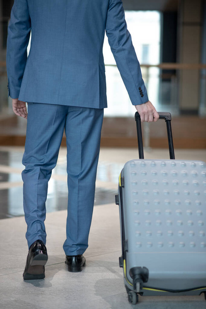 Businessman carrying his grey luggage while having business trip - Zdjęcie, obraz