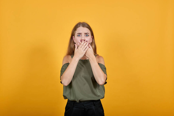 Young attractive blonde woman covering mouth with hands - Foto, afbeelding
