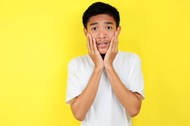 Schockiertes Gesicht eines asiatischen Mannes in weißem Hemd auf gelb - Foto, Bild