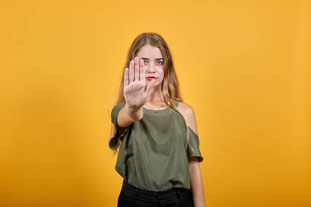 Portret poważnej młodej kobiety w luźnych ubraniach pokazujący gest zatrzymania - Zdjęcie, obraz