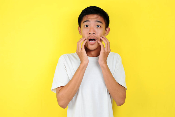 Shocked face of Asian man in white shirt on yellow - Photo, Image
