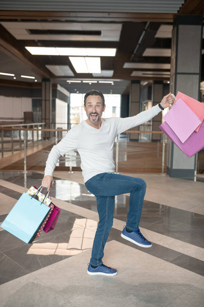 Man wearing jeans and sweater feeling cheerful after weekend shopping - Foto, immagini