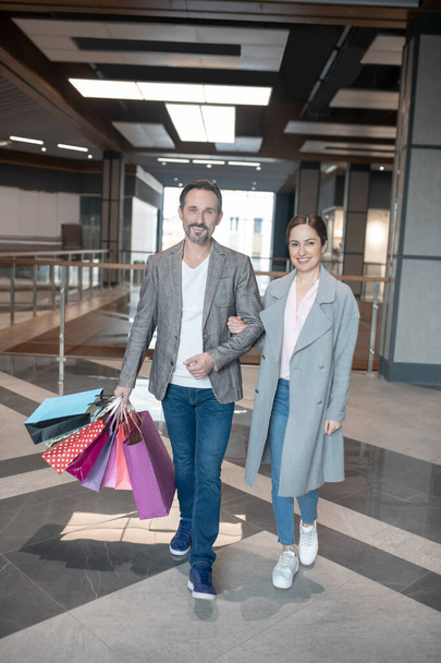 Couple smiling while leaving shopping center after successful shopping - Fotoğraf, Görsel