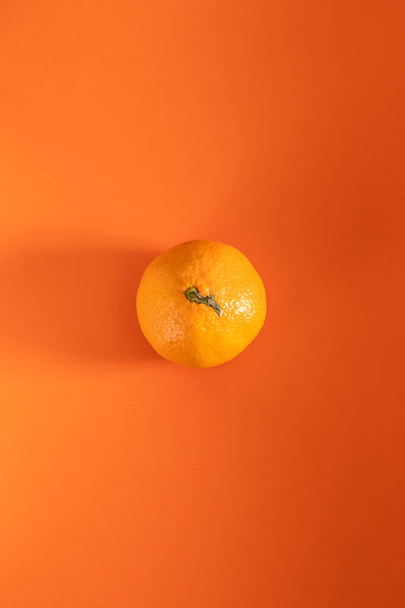 ripe mandarin lies on an orange background - 写真・画像