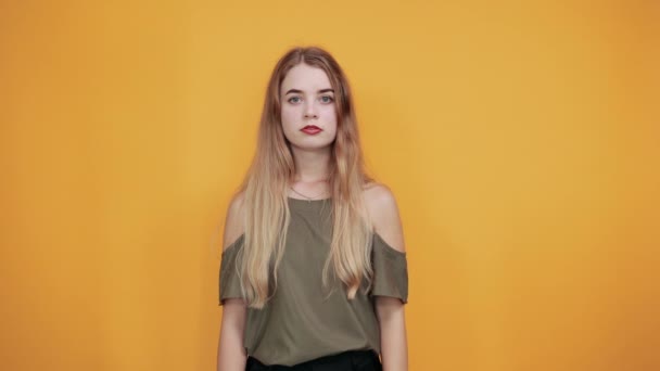 Giovane donna attraente che copre la bocca con le mani sulla parete arancione isolata
 - Filmati, video
