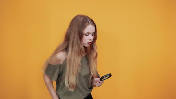 Νεαρή γυναίκα σε πουκάμισο μόδας κρατώντας ένα μεγεθυντικό φακό, αναζητούν σοβαρή - Πλάνα, βίντεο