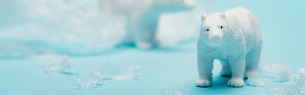 Foto panorámica de osos polares de juguete con basura de polietileno sobre fondo azul, concepto de contaminación ambiental
 - Foto, imagen