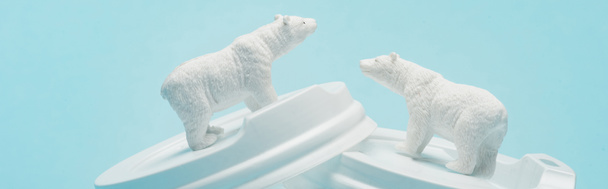 Foto panorámica de osos polares de juguete sobre tapas de café de plástico sobre fondo azul, concepto de bienestar animal
 - Foto, Imagen