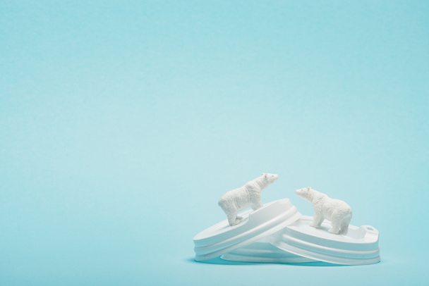 Due orsi polari giocattolo su coperchi di plastica caffè su sfondo blu, concetto di problema ecologico
 - Foto, immagini