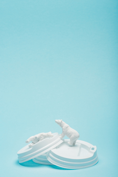 Orsi polari giocattolo su coperchi di caffè su sfondo blu, concetto di benessere degli animali
 - Foto, immagini