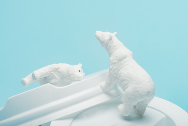 Toy polar bears on coffee lids on blue background, animal welfare concept - Photo, Image