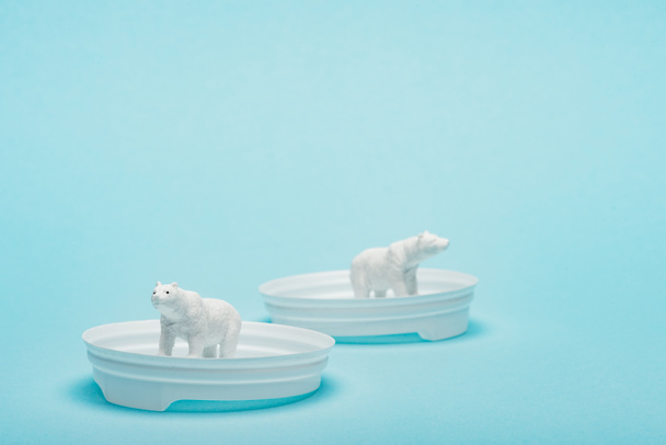 Osos polares de juguete en tapas de café de plástico sobre fondo azul con espacio para copias, concepto de bienestar animal
 - Foto, Imagen