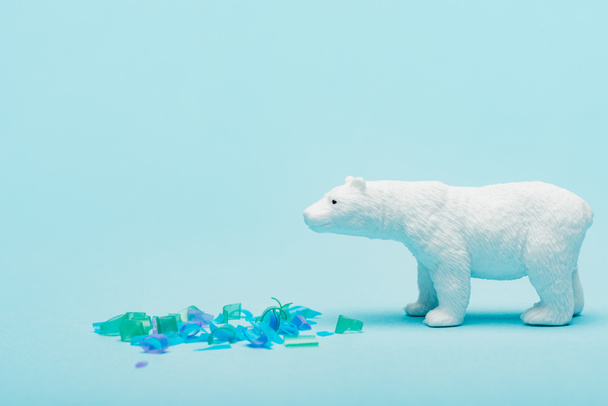 Lelu jääkarhu vieressä muovikappaleita sinisellä pohjalla, eläinten hyvinvoinnin käsite
 - Valokuva, kuva