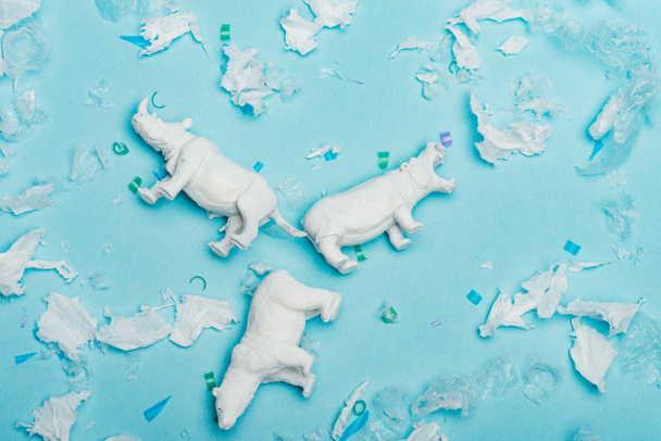 Pohled shora na hrocha, nosorožce a medvědí hračky s plastovým odpadem na modrém pozadí, koncept dobrých životních podmínek zvířat - Fotografie, Obrázek