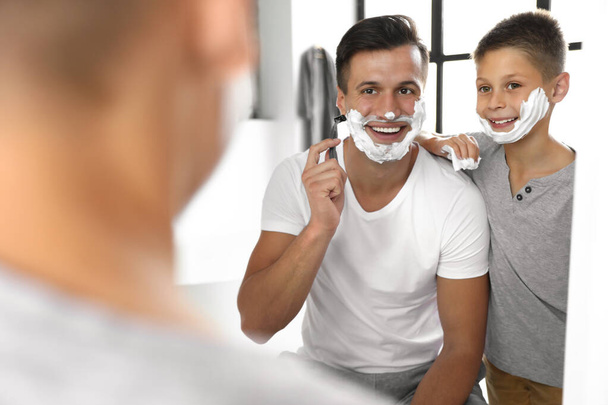 Dad showing his son how to shave near mirror in bathroom - Foto, Imagen