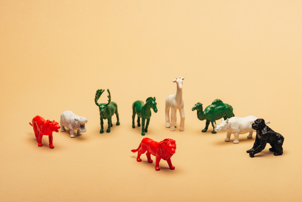 Sarı arka planda renkli oyuncak hayvanları olan kırmızı aslan, hayvanların nesli tükenme kavramı. - Fotoğraf, Görsel