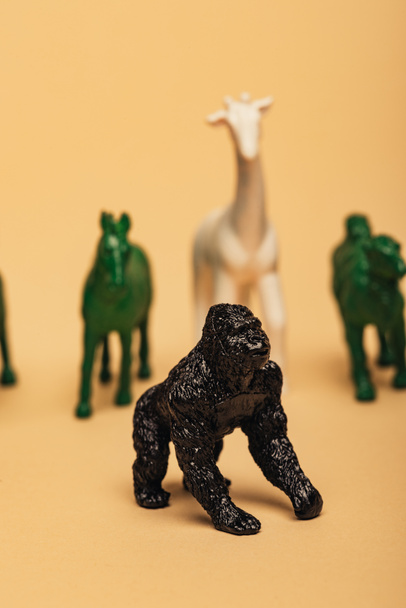 Selective focus of gorilla with colored toy animals on yellow background, extinction of animals concept - Foto, Bild