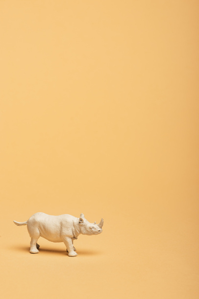 White toy rhinoceros on yellow background, animal welfare concept - Photo, Image
