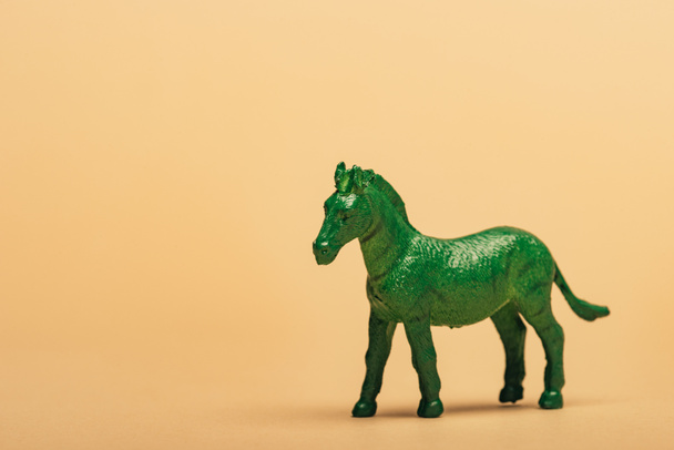 Green toy horse on yellow background, animal welfare concept - Photo, Image