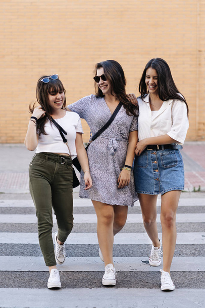 junge weibliche Gruppe von drei Freundinnen, die lächelnd und anblickend th - Foto, Bild