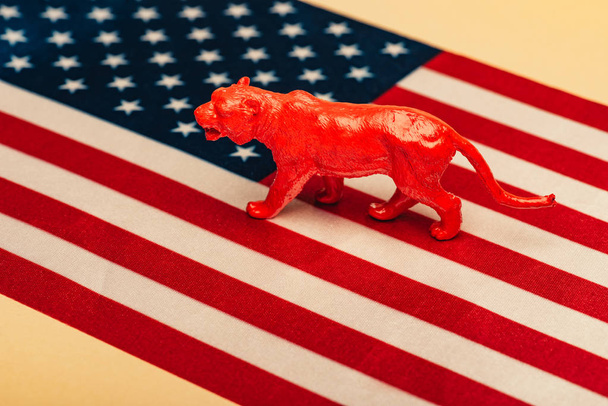 Tigre de brinquedo vermelho na bandeira americana no fundo amarelo, conceito de bem-estar animal
 - Foto, Imagem