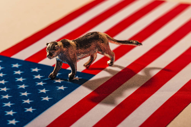 Golden toy tiger with shadow on american flag, animal welfare concept - Fotó, kép