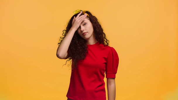atrakcyjna dziewczyna pokazując gest wzruszenia odizolowany na pomarańczowy  - Materiał filmowy, wideo